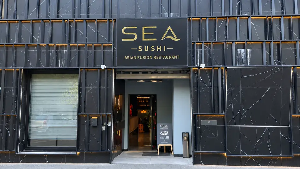 Sea Sushi 的门面：黑色外墙，入口上方是金色的 SEA SUSHI 招牌