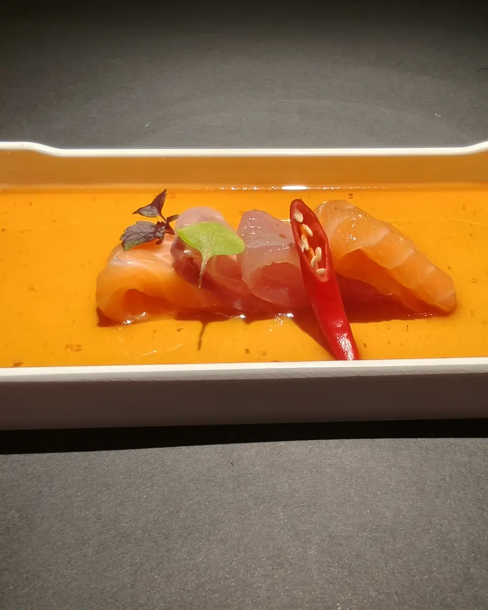 Carpaccio di salmone e pesce bianco in salsa all'arancia, su un vassoio rettangolare