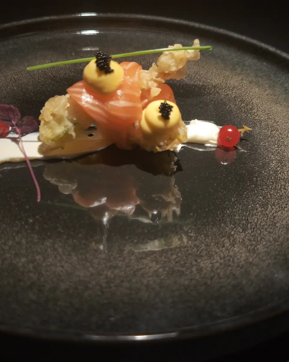 Bocconcino di salmone in tempura con caviale e salsa, su piatto scuro