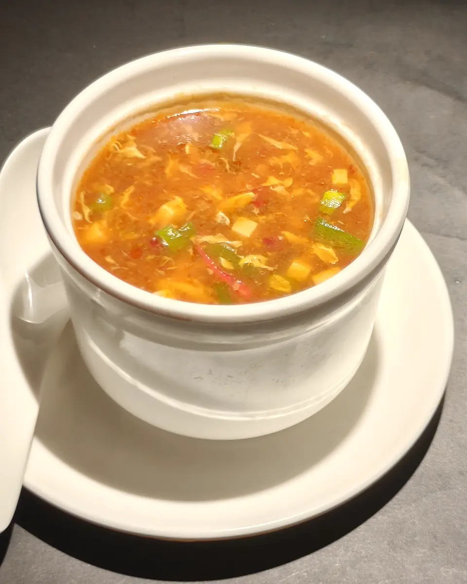 Zuppa agropiccante in una tazza bianca con il cucchiaio