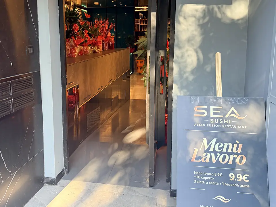 Il cartello del Menù Lavoro all'ingresso, accanto alla porta aperta sul corridoio con i fiori